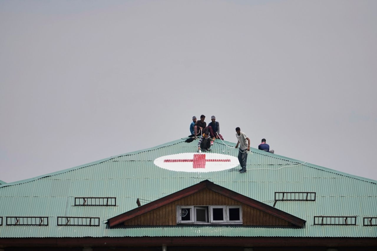 Рабочие рисуют красный крест на крыше больницы на подконтрольной Индии территории Кашмира