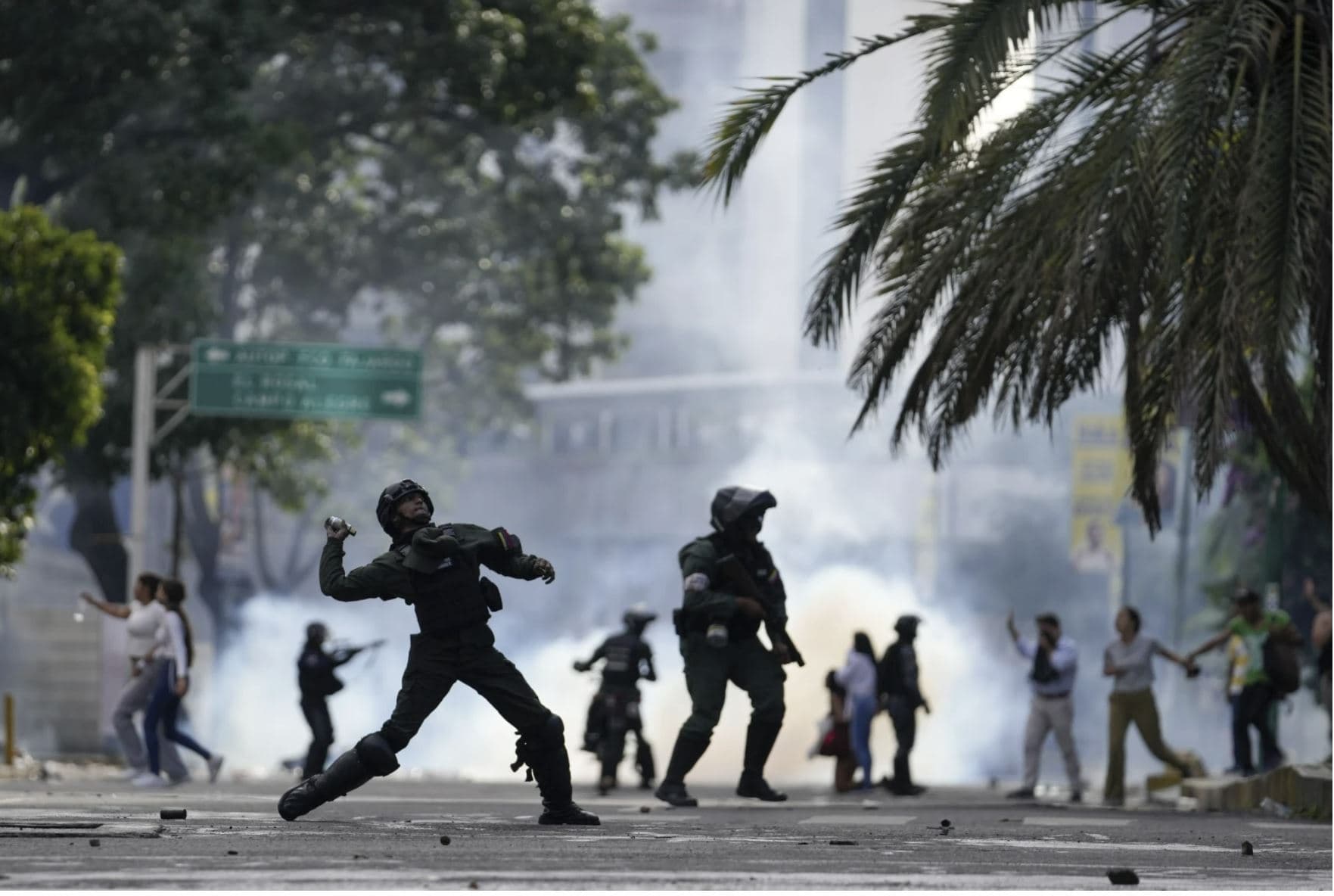 Cтолкновения между полицией и протестующими в Венесуэле. Полицейский бросает газовый баллончик в протестующих