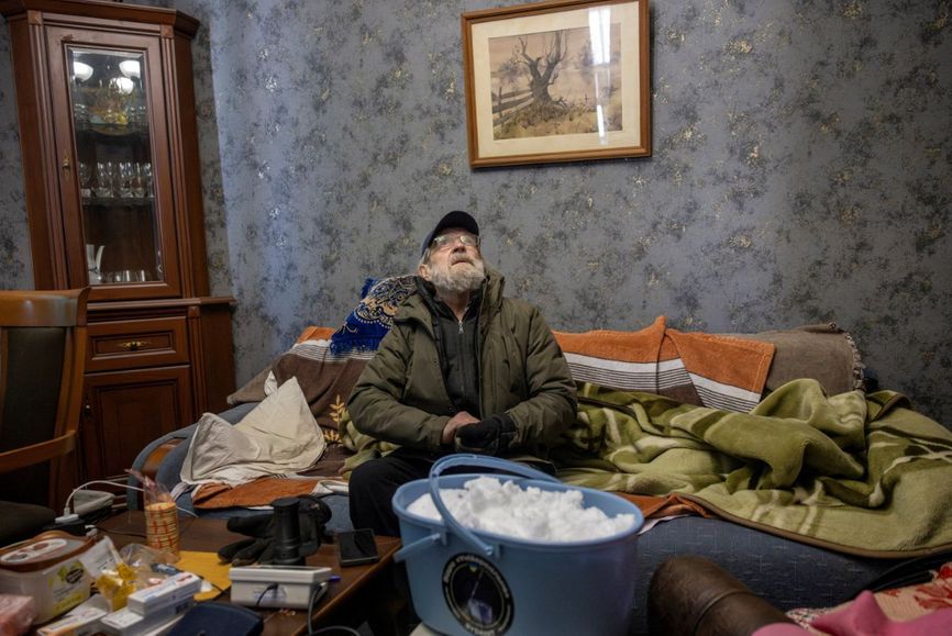 Житель Киева с ведром снега в своей квартире, 10 января 2026 года