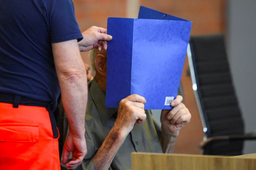 Йозеф Шютц на всех фотографиях из суда закрывает лицо папкой