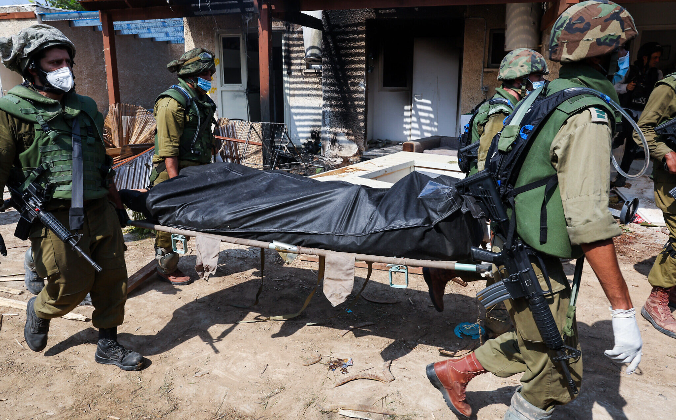 Израильские солдаты несут тело в кибуце Кфар-Аза