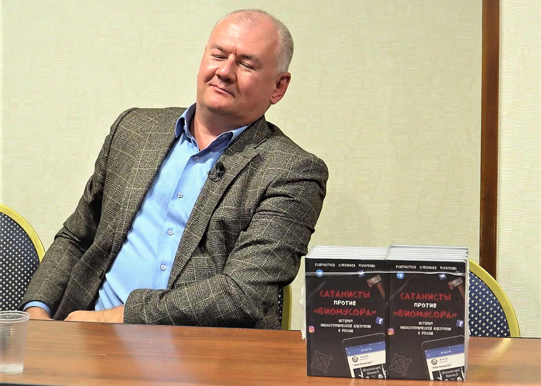 Roman Silantyev at the September 16 lecture for the Russian Community. The book on the table reads “Satanists against Biological Garbage”