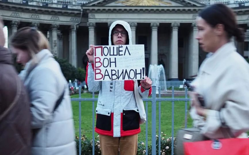 Dmitry Kuzmin holding up a poster against Vladimir Putin in front of the Kazan Cathedral in St. Petersburg.