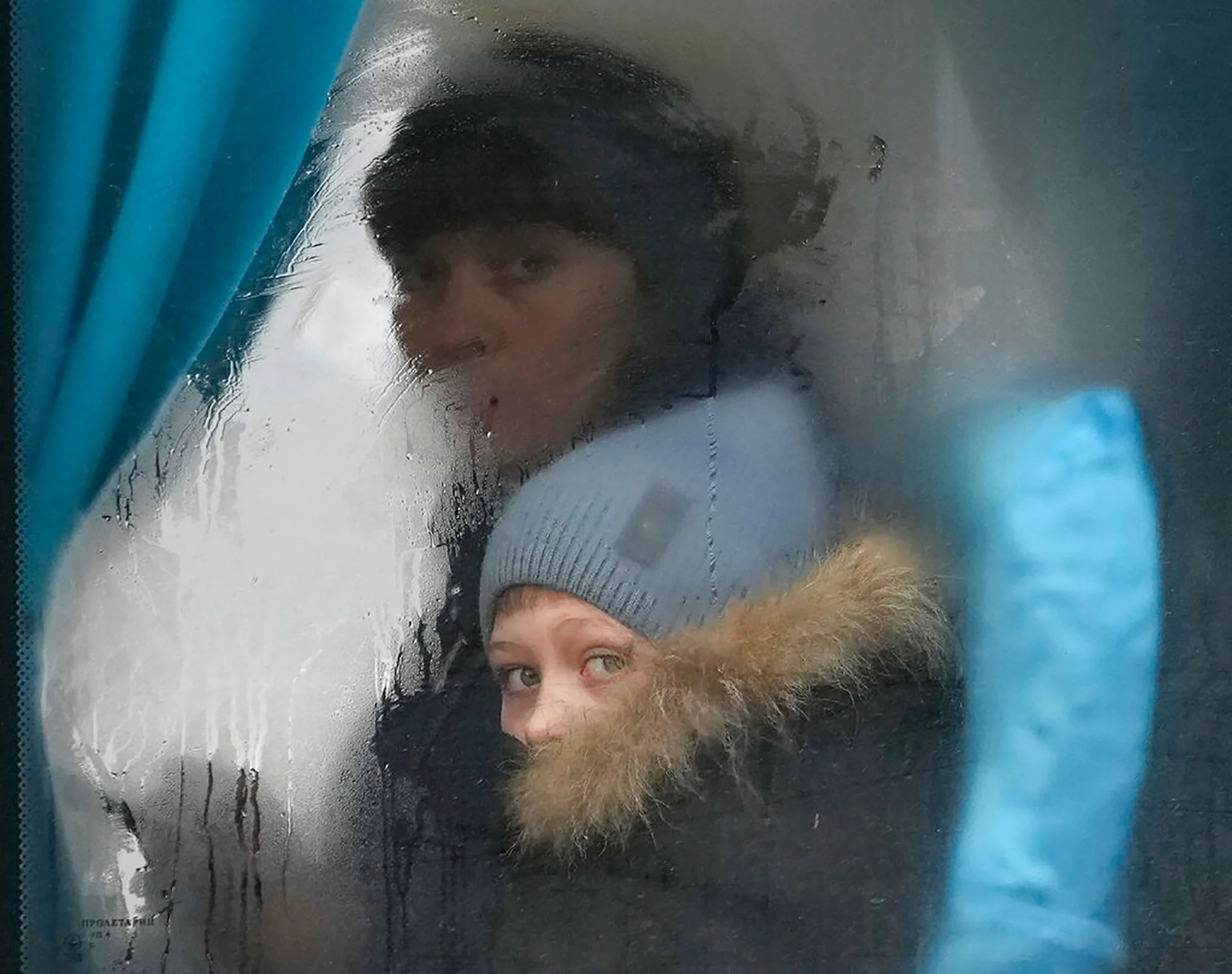 Женщина и ребенок выглядывают из окна автобуса на выезде из Северодонецка, Луганская область, Украина, 24 февраля